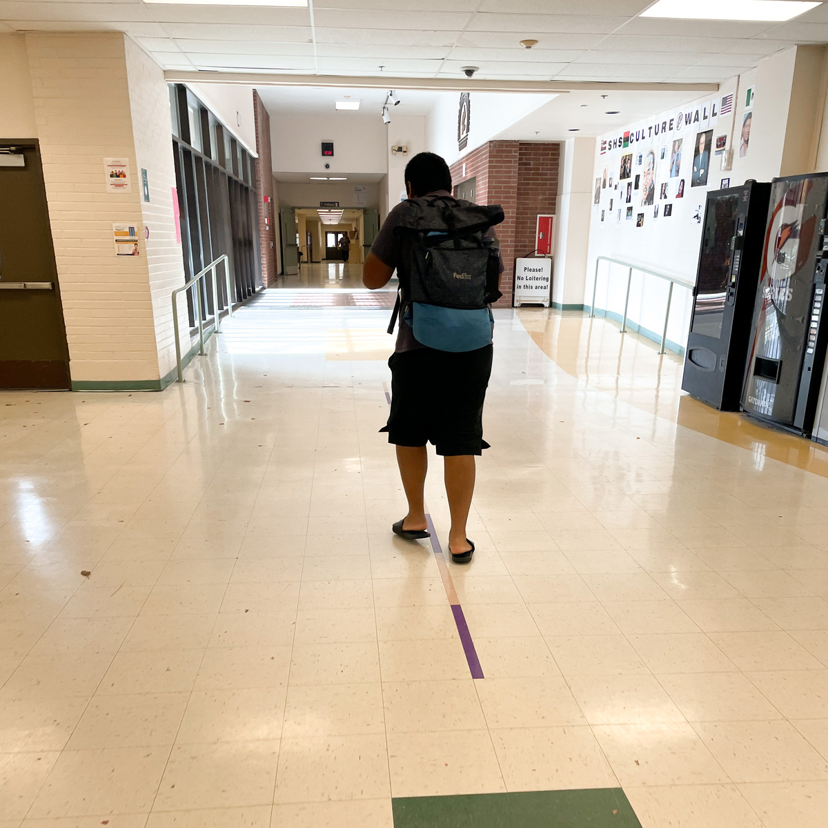 An image of an Autistic teenager walking down the halls of his high school.